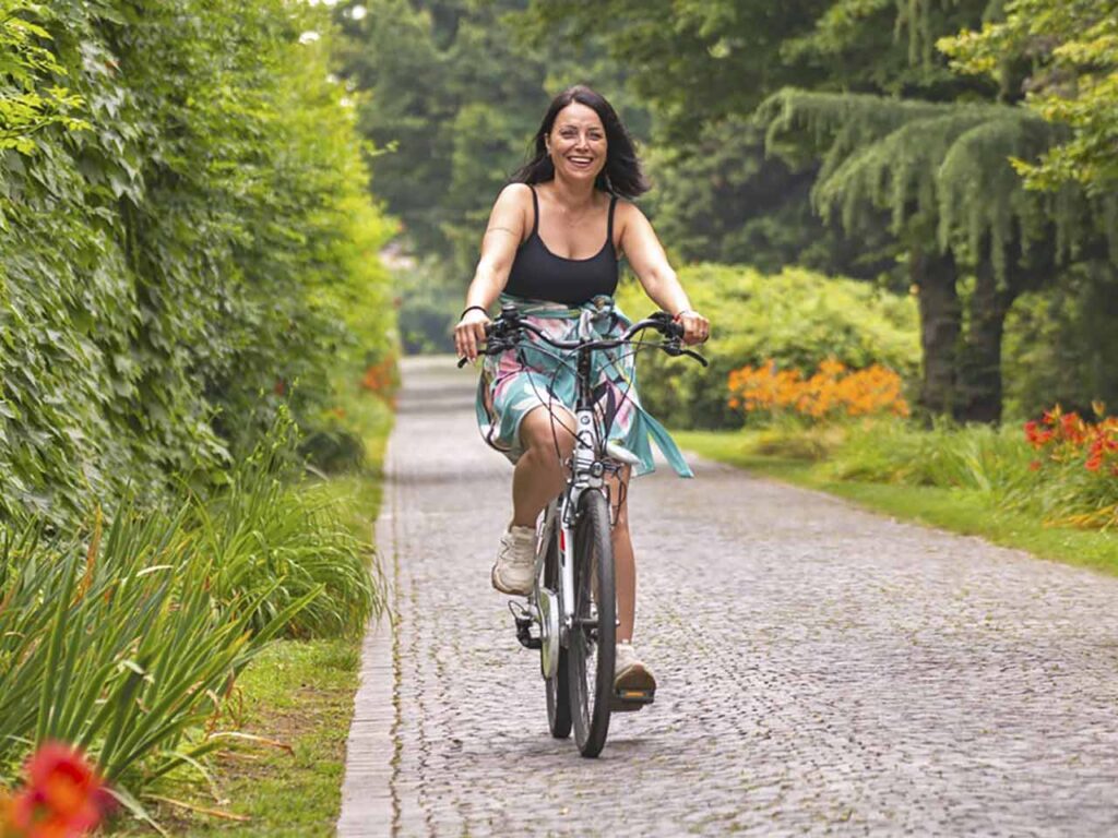 Ragazza in bicicletta lungo un viale del Parco Giardino Sigurtà a Valeggio sul Mincio.