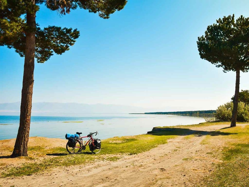 Una bici lungo un percorso ciclabile sterrato a bordo di un lago.