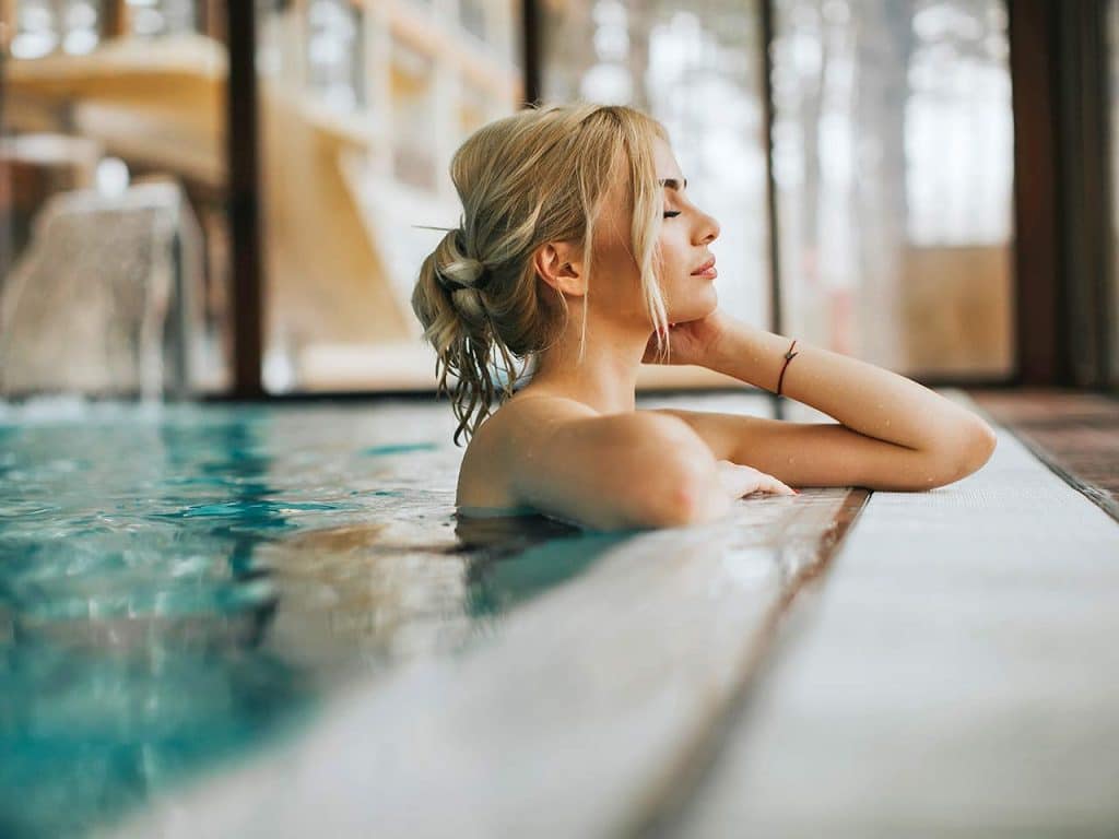 Una ragazza si gode un bagno nell'acqua calda benefica delle terme, una delle cose da fare questo inverno in camper suggerite dal PLEINAIRCLUB.
